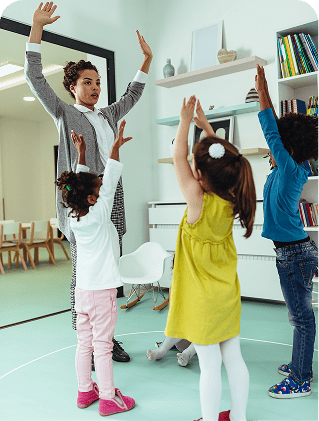 Children with teacher raising hands in classroom